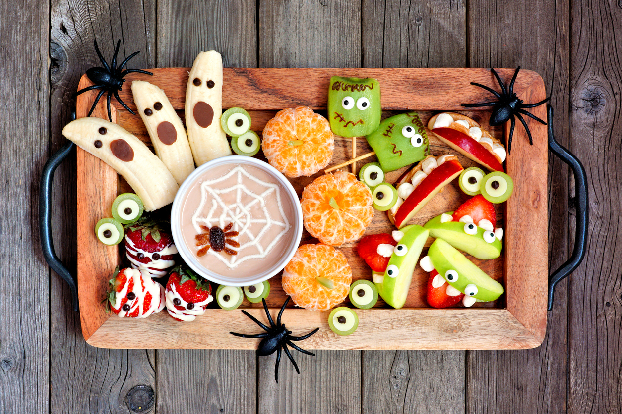 Halloween dental tips, Healthy Halloween fruit snacks. Tray of fun, spooky treats. Top view over a rustic wood background.