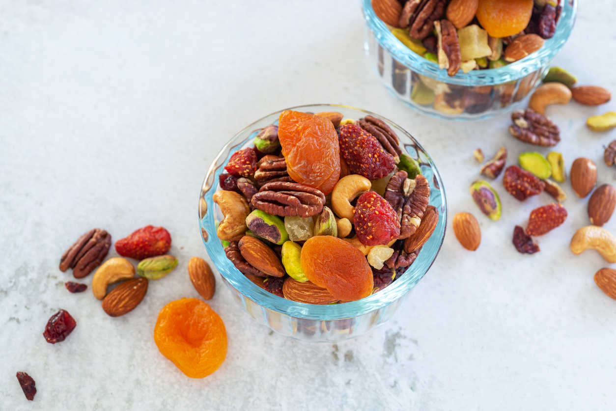 Halloween dental tips, mixed nut and dried fruit in glass bowl on white table background.