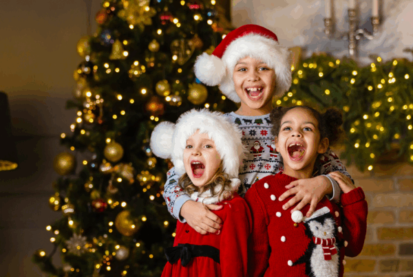 Holiday Dental Tips, three kids laughing in front of a christmas tree