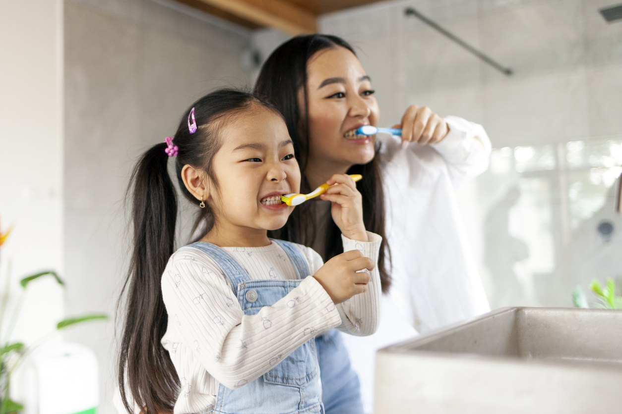 Why kids get cavities, asian little girl with mom brushing teeth in bathroom, korean woman helping to brush daughter's teeth at home together, asian family and hygiene procedures